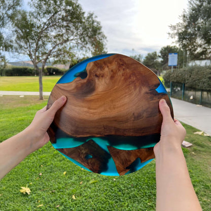 Handheld Epoxy Resin Art Piece with Natural Wood Grain Displayed Outdoors